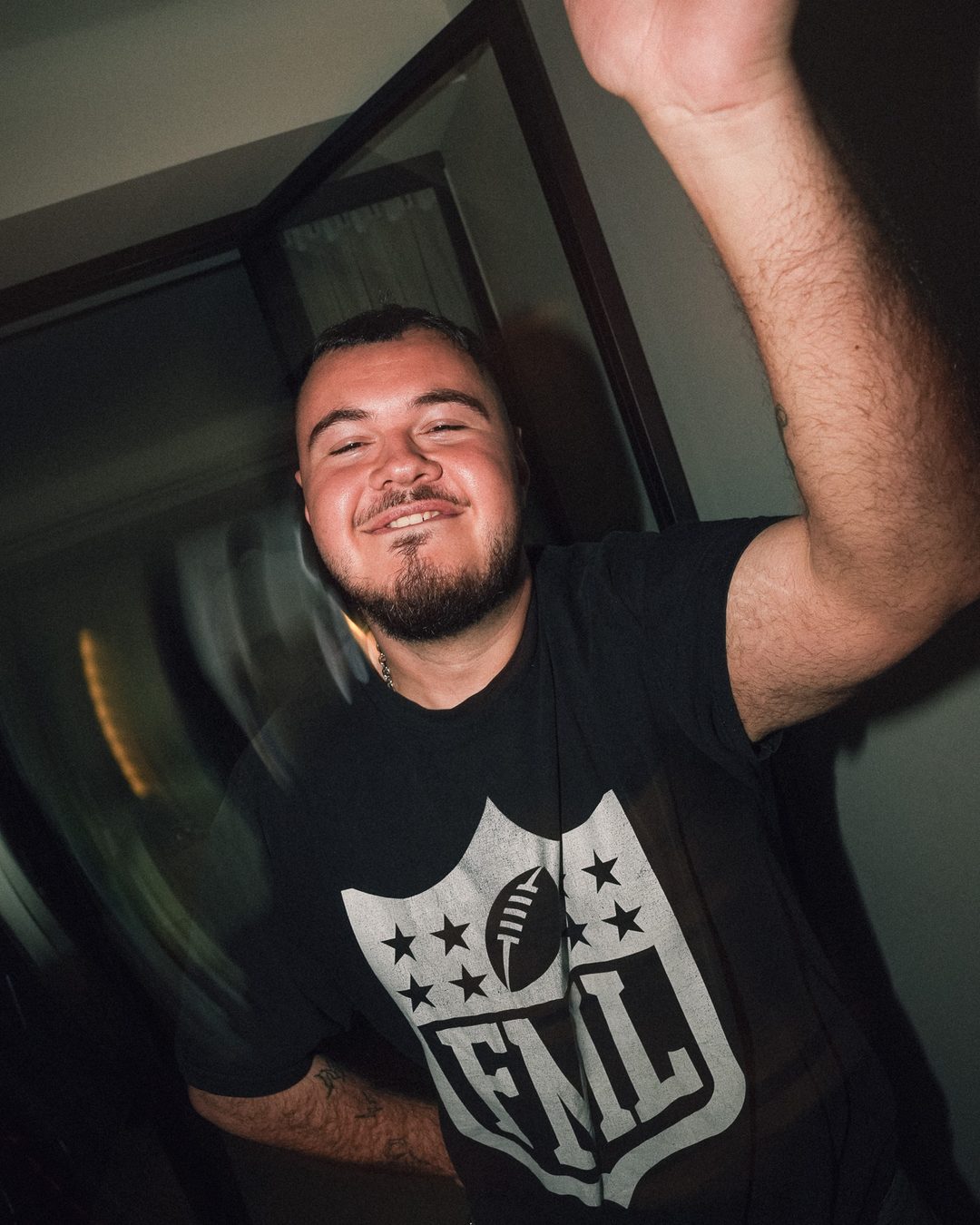 Guest in an FML t-shirt dancing with his arm in the air, Seraya AW1 party — photo by vinny.mp4, Stockholm